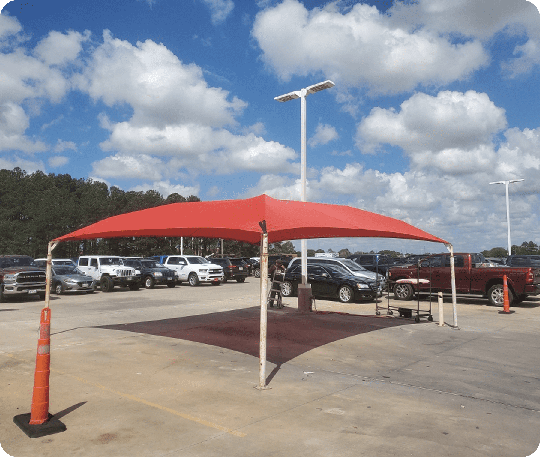 Red canopy in parking lot under clouds.