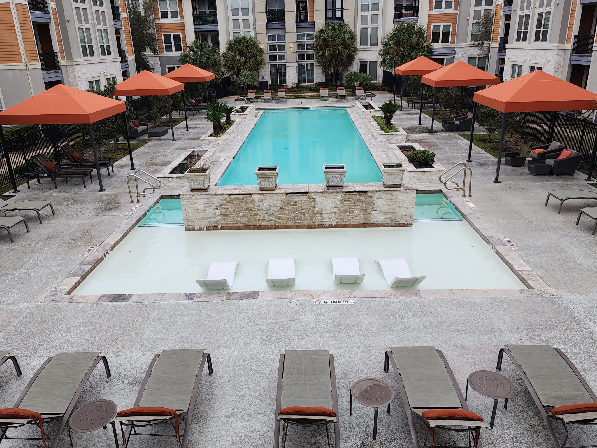 Modern outdoor pool area with lounge chairs and orange umbrellas.