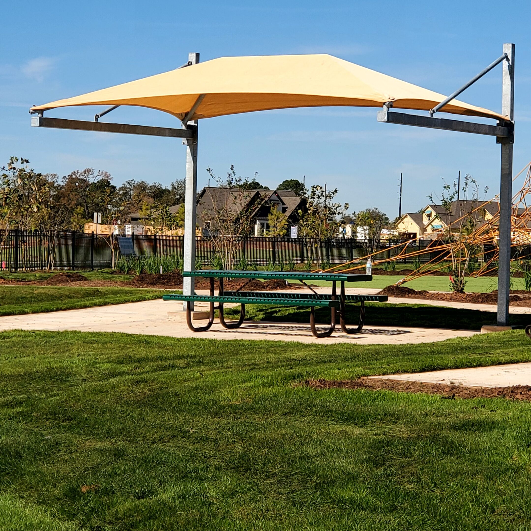 Picnic table with shade umbrella in a sunny park.